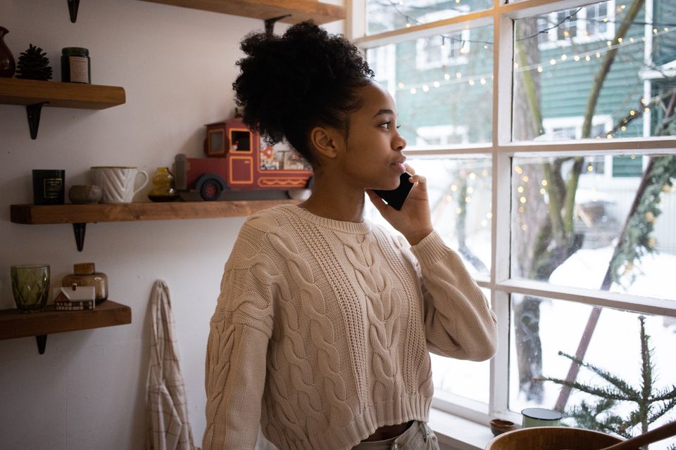 A woman making an unhurried phone call beside a bright window