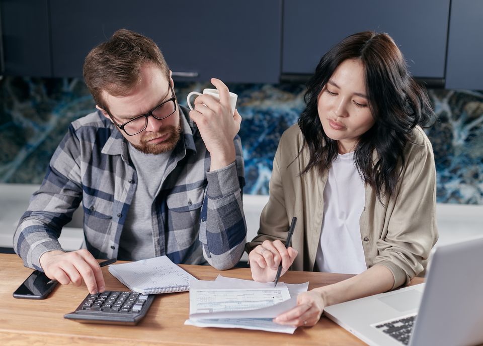 Couple planning together at a table with a calculator and laptop