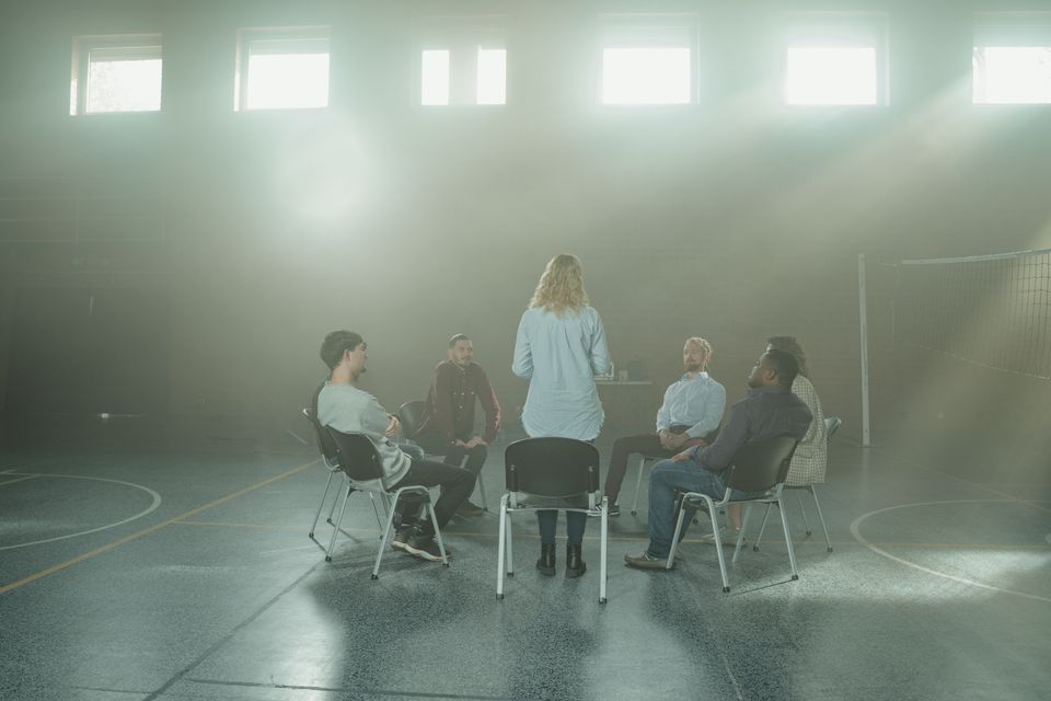 A group of adults talking together in a sunlit room